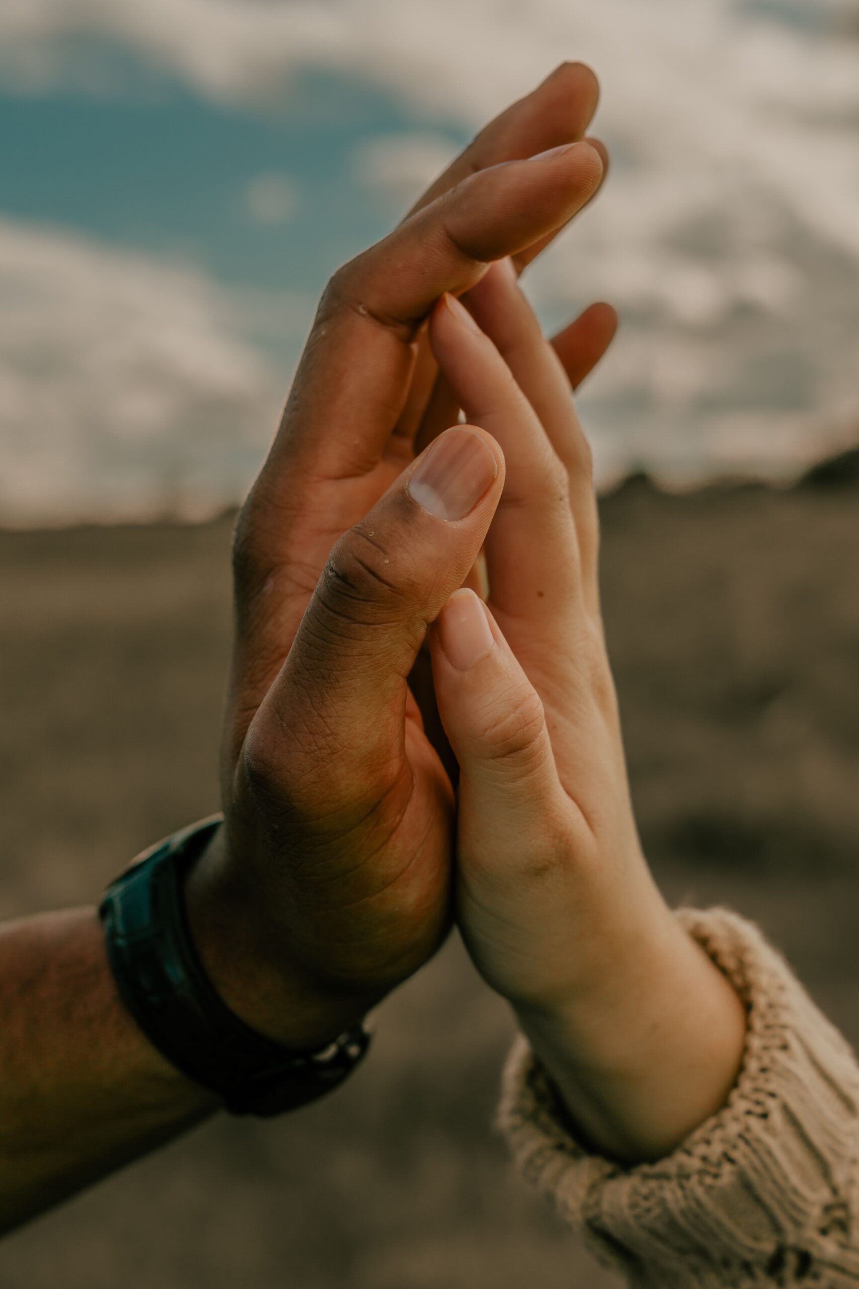 two people in a field touching hands for support